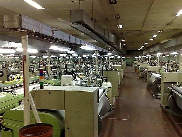 Long rows of weaving looms under strip lighting