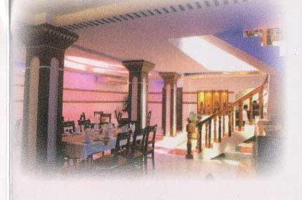 A dining hall with laid tables, columns, and a staircase to the upper floor
