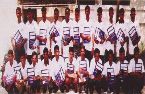 A batch of workers in matching shirts holding their travel documents before departure