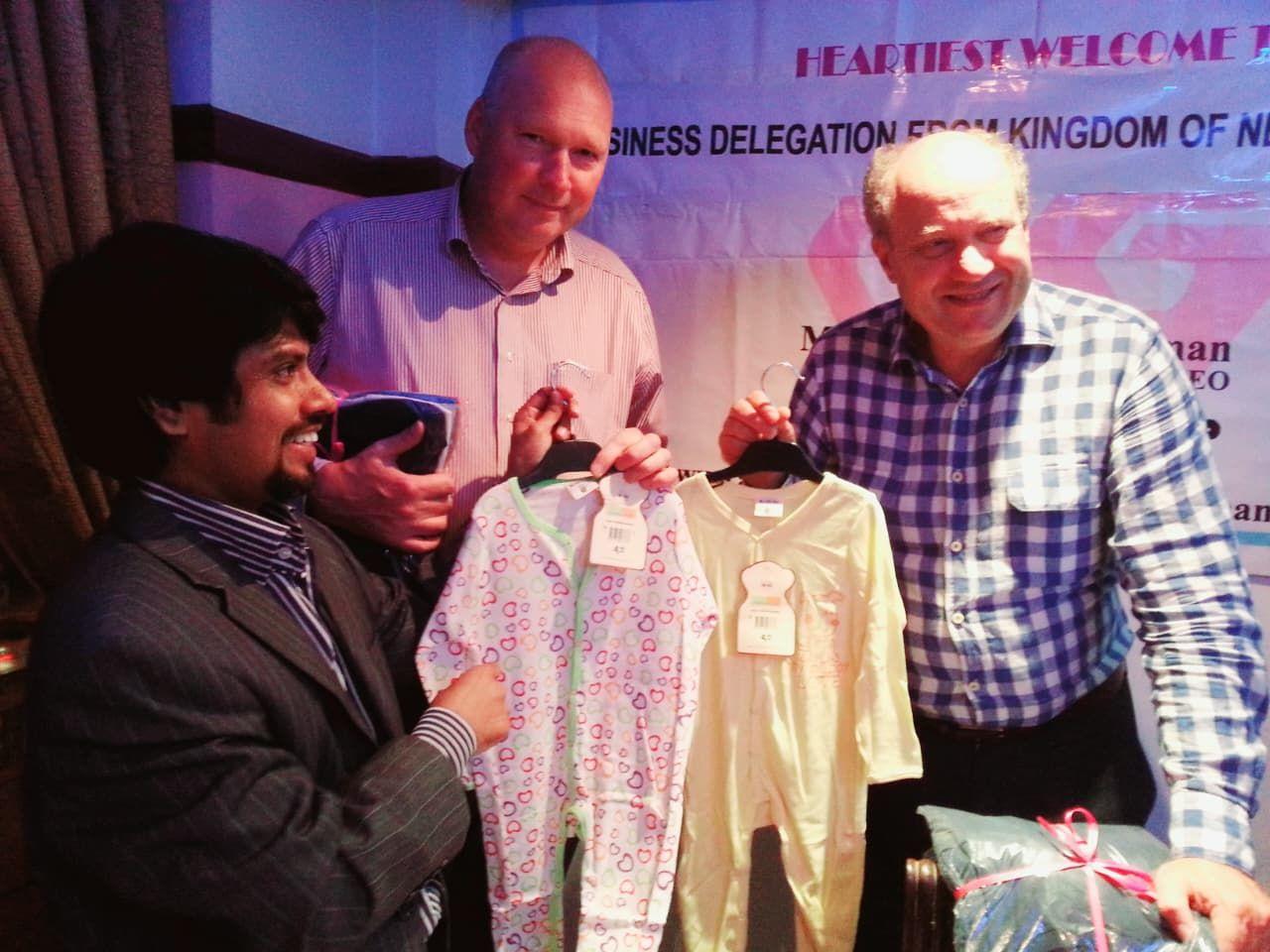 Members of a business delegation from the Netherlands holding Rahtex baby sleepsuits