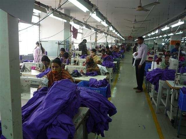 Operators sewing purple garments on a production line