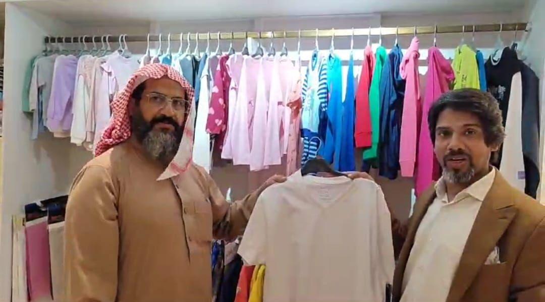 A buyer and the Chairman with a shirt in front of a rail of sample garments